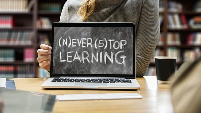 Person lächelt während des Lernens an einem Laptop, zeigt Motivation und Freude.
