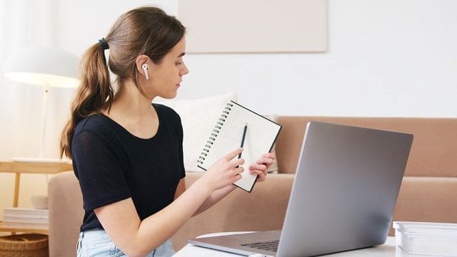 Lernende nimmt online an einem flexiblen Deutschkurs mit Laptop und Notizbuch teil
